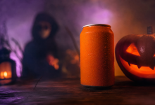 Lata de refrigerante em cenário de Halloween com iluminação roxa e laranja e figura mascarada ao fundo.