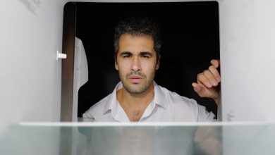 Homem preocupado olha para dentro de uma geladeira vazia em uma cozinha.