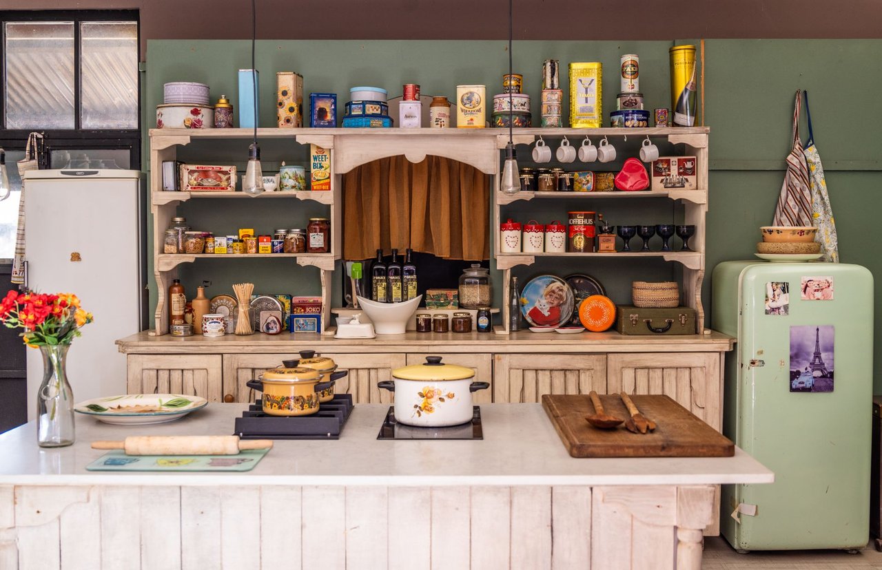 Cozinha vintage com eletrodomésticos, utensílios e objetos decorativos coloridos, criando uma atmosfera nostálgica.