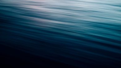 Ondas do mar em movimento suave, com efeito de desfoque e luz crepuscular em tons azulados.