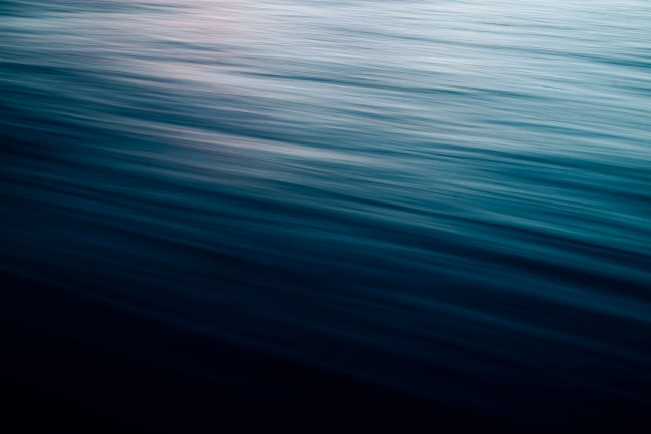 Ondas do mar em movimento suave, com efeito de desfoque e luz crepuscular em tons azulados.