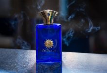 Frasco de perfume envolto por uma atmosfera esfumaçada, em composição escura e abstrata.